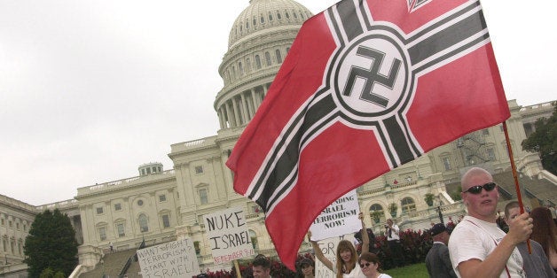 WASHINGTON, : An unidentified member of the Neo-Nazi National Alliance parades a flag with a swastika in front of the US Capitol during a rally of about 300 demonstrators, 24 August 2002 in Washington, DC. The members, who were met by counter-demonstrators on the march but avoided violence, were protesting American aid and support to Israel. AFP PHOTO/MIKE THEILER (Photo credit should read MIKE THEILER/AFP/Getty Images)