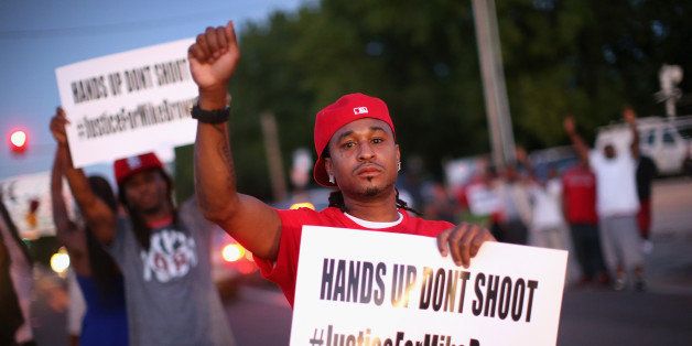 ST. LOUIS, MO - AUGUST 12: Demonstrators protest the killing of teenager Michael Brown outside Greater St. Marks Family Church while Browns family along with civil rights leader Rev. Al Sharpton and a capacity crowd of guests met inside to discuss the killing on August 12, 2014 in St Louis, Missouri. Brown was shot and killed by a police officer on Saturday in the nearby suburb of Ferguson. Ferguson has experienced two days of violent protests since the killing but, tonight the town remained mostly peaceful. (Photo by Scott Olson/Getty Images)