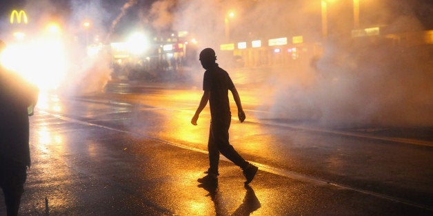 FERGUSON, MO - AUGUST 17: Police fire tear gas at demonstrators protesting the shooting of Michael Brown after they refused to honor the midnight curfew on August 17, 2014 in Ferguson, Missouri. The curfew was imposed on Saturday in an attempt to reign in the violence that has erupted nearly every night in the suburban St. Louis town since the shooting death of teenager Michael Brown by a Ferguson police officer on August 9. (Photo by Scott Olson/Getty Images)