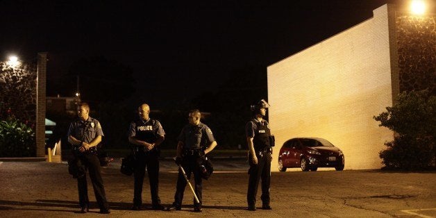 Police in riot gear stand in position as demonstrators protest the shooting death of Michael Brown August 20, 2014 in Ferguson, Missouri. St. Louis County Prosecutor Bob McCullough has not filed any charges against Ferguson Police Officer Darren Wilson, after Wilson fatally wounded Brown August 9th. AFP PHOTO/Joshua LOTT (Photo credit should read Joshua LOTT/AFP/Getty Images)