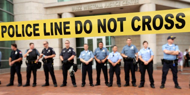 Police guard the entrance to the Buzz Westfall Justice Center in Clayton, Mo., Wednesday, Aug. 20, 2014, where a grand jury is expected to convene to consider possible charges against the Ferguson, Mo. police officer who fatally shot 18-year-old Michael Brown. Brown's shooting in the middle of a street has sparked a more than week of protests, riots and looting in the St. Louis suburb. (AP Photo/Charlie Riedel)