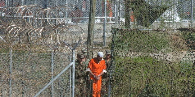 FILE - In this March 1, 2002 file photo, a detainee is escorted to interrogation by U.S. military guards at Camp X-Ray at Guantanamo Bay U.S. Naval Base, Cuba. Three detainees from Guantanamo Bay have been transferred from the island prison to the country of Georgia. The Justice Department says the identities of the three detainees sent to Georgia on Tuesday March 23, 2010, are being withheld for security and privacy reasons. (AP Photo/Andres Leighton, File)