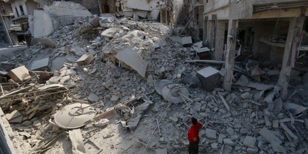 A Syrian man looks at the rubble of a five story apartment building that was destroyed in a barrel bomb attack in the al-Shaa