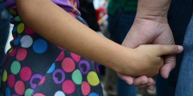 A woman and her daughter hold hands as she speaks to the press upon arriving in San Pedro Sula, about 260 km north of Tegucigalpa, on July 14, 2014 after being deported from the United States. A first group of 120 deportees from Honduras, El Salvador and Guatemala who had crossed into the United States illegally were repatriated by plane to their countries -- most of them unaccompanied youths. US authorities have detained some 57,000 unaccompanied minors since October, twice the number from the same period a year ago, seeking to illegally cross into the US from Mexico. AFP PHOTO/Orlando SIERRA (Photo credit should read ORLANDO SIERRA/AFP/Getty Images)