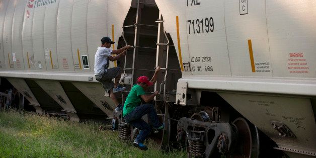 In this Aug. 26, 2014 photo, Central American migrants jump onto a moving freight train as it departs from Arriaga, Chiapas state, Mexico. In contrast to the many hundreds of migrants who used to board the train in Arriaga, only three could be seen jumping on on this day. Several dozen others emerged from wooded areas to hop aboard in the several kilometers outside Arriaga. (AP Photo/Rebecca Blackwell)