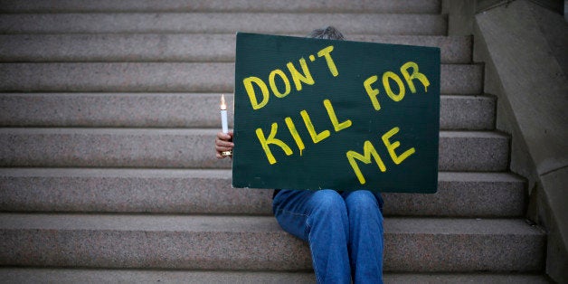 Death penalty opponent Joyce Engle holds a sign as she sits on the stairs of St. Francis Xavier College Church during a vigil hours before the scheduled execution of Missouri death row inmate Russell Bucklew on Tuesday, May 20, 2014, in St. Louis. A federal appeals court has granted a stay of execution for Bucklew, hours before he was scheduled to die for killing a southeast Missouri man in 1996. The 8th U.S. Circuit Court of Appeals on Tuesday cited concerns about Russell Bucklews' rare medical condition, which raised the risk of "unnecessary pain and suffering by the inmate." (AP Photo/Jeff Roberson)