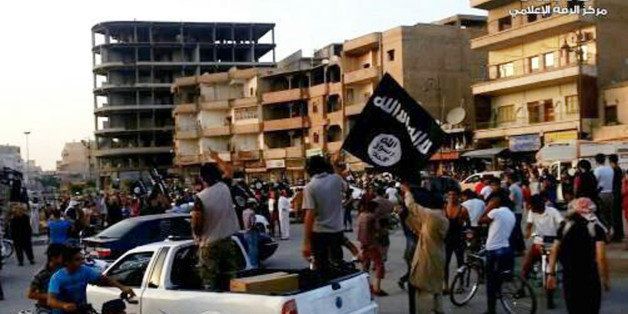 This undated image posted by the Raqqa Media Center, a Syrian opposition group, on Monday, June 30, 2014, which has been verified and is consistent with other AP reporting, shows fighters from the al-Qaida linked Islamic State of Iraq and the Levant (ISIL) during a parade in Raqqa, Syria. Militants from an al-Qaida splinter group held a military parade in their stronghold in northeastern Syria, displaying U.S.-made Humvees, heavy machine guns, and missiles captured from the Iraqi army for the first time since taking over large parts of the Iraq-Syria border. (AP Photo/Raqqa Media Center)