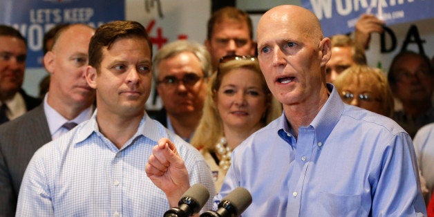 Florida Gov. Rick Scott, right, with running mate for Lt. Gov., Carlos Lopez-Cantera, front left, makes remarks to supporters at a campaign event Monday, Sept. 8, 2014, in Winter Park, Fla. Scott is running against former Republican Gov. Charlie Crist, who is running as a Democrat in November's election for Florida governor. (AP Photo/John Raoux)