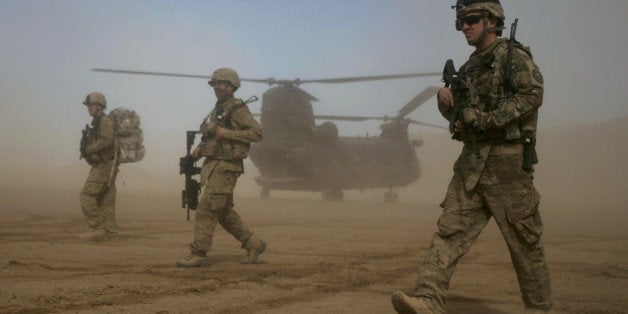 U.S. soldiers part of the NATO- led International Security Assistance Force (ISAF) walks, as a U.S. Chinook helicopter is seen on the back ground near the place where the foundation of a hospital was laid in Shindand, Herat, west of Kabul, Afghanistan, Saturday, Jan. 28, 2012. The foundation of a U.S. military funded 50 beds hospital was laid with the cost of 400, 000 US dollar in Shindand of Herat, the hospital project is expected to be completed in 18 months. (AP Photo/Hoshang Hashimi)