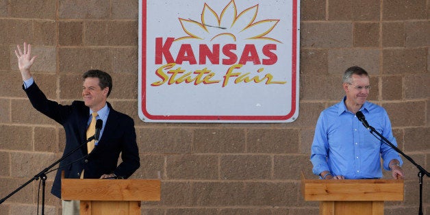 Republican Gov. Sam Brownback, left, and his Democratic challenger, Paul Davis acknowledge supporters after a debate at the Kansas State Fair Saturday, Sept. 6, 2014, in Hutchinson, Kan. (AP Photo/Charlie Riedel)