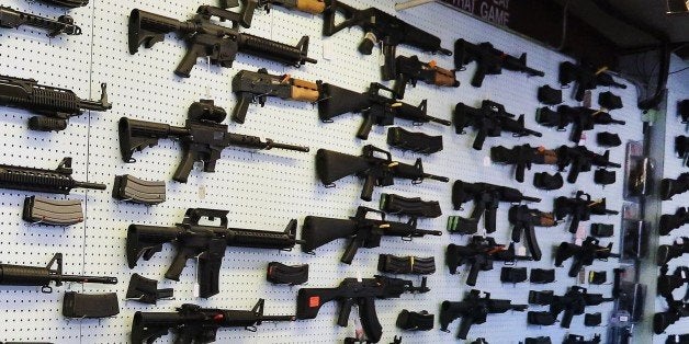 In this July 20, 2014 photo, with guns displayed for sale behind her, a gun store employee helps a customer at Dragonman's, e