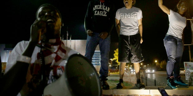 A small group of people protest outside the police station Friday, Sept. 26, 2014, in Ferguson, Mo. The night was relatively calm following clashes between police and protesters on Thursday evening. (AP Photo/Jeff Roberson)