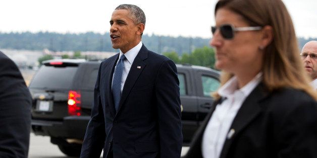 Flanked by Secret Service agents, President Barack Obama arrives in Seattle, Tuesday, July 22, 2014, the start of a three-day West Coast trip that is planned to include at least five fundraising events in Seattle, San Francisco and Los Angeles. (AP Photo)