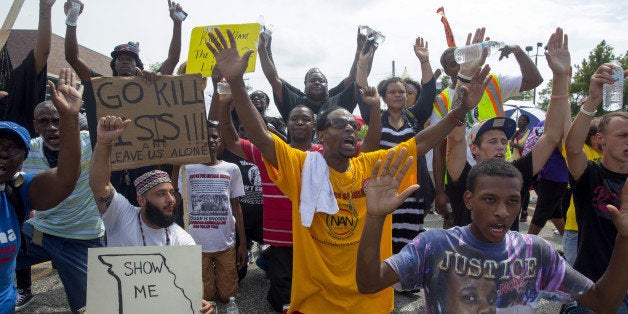 FERGUSON, MO - AUGUST 30: Protesters sit down in the street outside the police department during a protest over the killing of Michael Brown August 30, 2014 in Ferguson, Missouri. Michael Brown, an 18-year-old unarmed teenager, was shot and killed by Ferguson Police Officer Darren Wilson on August 9. His death caused several days of violent protests along with rioting and looting in Ferguson. (Photo by Aaron P. Bernstein/Getty Images)