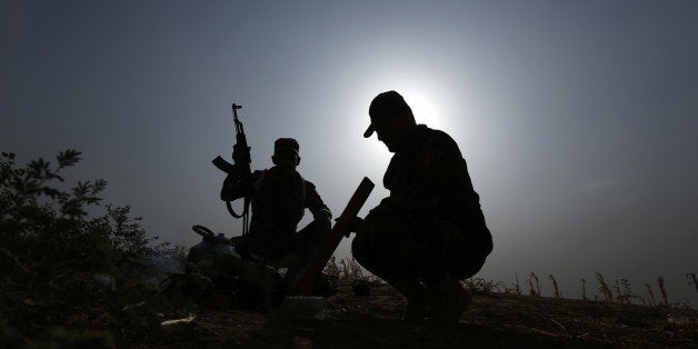 Iraqi Kurdish soldiers pause from combat to make tea near to the front line in Mahmoudiyah, Iraq, a day after they take contr
