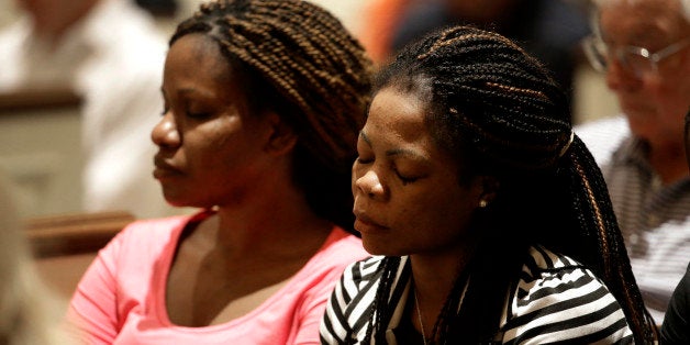 Princess Duo, left, and Mamie Mangoe, right, both natively of Liberia who now live in Dallas, bow their head in prayer during a service at Wilshire Baptist Church that was dedicated to Thomas Eric Duncan, Wednesday, Oct. 8, 2014, in Dallas. Nearly 150 persons attended the service for Duncan who died Wednesday of complication from Ebola. (AP Photo/Tony Gutierrez)