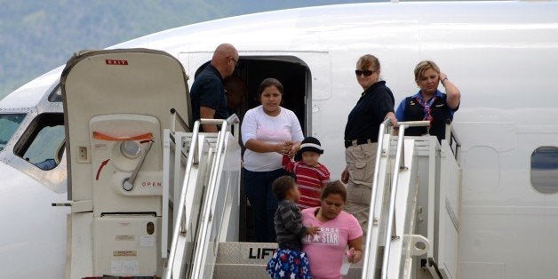 Two women and their children descend for a plane at Palmerola air base in Comayagua, 80 km north of Tegucigalpa on August 11, 2014 after being deported from the US where they had entered illegally. Tens of thousands of migrants - adults and minors - are making the treacherous journey from impoverished Central America to the United States in search of a better life. At least 57,000 children have made the journey since October, triggering a migration crisis that has sent US border and immigration authorities into a frenzy. AFP PHOTO/Orlando SIERRA (Photo credit should read ORLANDO SIERRA/AFP/Getty Images)