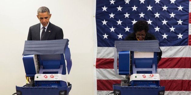 President Barack Obama, left, cast a ballot for the 2014 midterm elections at the Dr. Martin Luther King Community Service Center while participating in early voting on Monday, Oct. 20, 2014, in Chicago. Obama took a break from campaigning for Gov. Pat Quinn, D-Ill., to cast an early ballot for the election. (AP Photo/Evan Vucci)