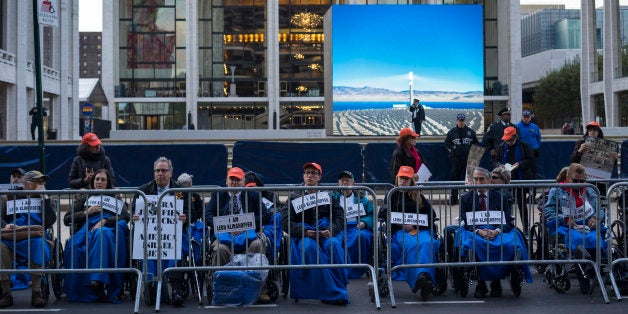 People, some in wheelchairs, gather at Lincoln Center, with the Metropolitan Opera House in the background, as they protest "Death of Klinghoffer" Monday, Oct 20, 2014, in New York. American composer John Adams' opera has been a lightning rod since February, when it was first scheduled for this season. The first large demonstration came on the Met's Sept. 22 season opening night, featuring a Mozart work, when protesters jeered at arriving spectators. (AP Photo/Craig Ruttle)