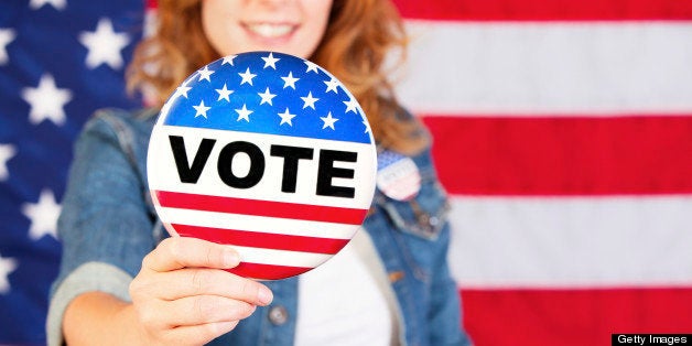 Young woman holding a large vote pin.