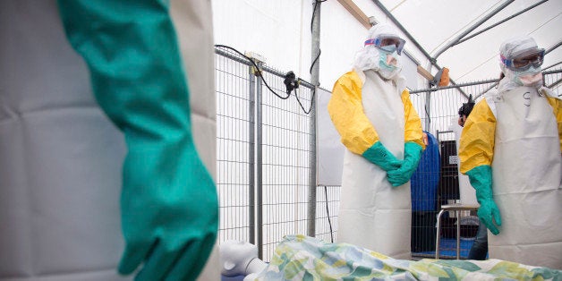 During a training session participants listen as they stand over a mannequin on a stretcher during a training course to instruct non-governmental organisation (NGO) workers and doctors on how to deal with the Ebola virus in Brussels on Tuesday, Aug. 26, 2014. The course, provided by Doctors Without Borders, trains volunteer and medical personnel on precautions to take when entering a zone that contains the Ebola virus.(AP Photo/Olivier Matthys)