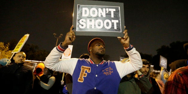 Protesters gather across the street from the Ferguson, Mo., police station in a continuing protest of the shooting of Michael Brown, Friday, Oct. 10, 2014, in Ferguson, Mo. (AP Photo/Charles Rex Arbogast)