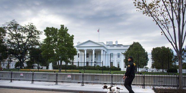 A US Secret Service Uniformed Division officer and his K-9 dog patrol the fence line of the White House in Washington, DC, October 23, 2014. A suspect who climbed over the White House fence on October 22 was nabbed by Secret Service agents and dogs, a spokesman for the elite agency said. 'At approximately 7:16 pm (1116 GMT), an individual climbed the north fence line of the White House,' the spokesman said. 'The individual was immediately taken into custody on the north lawn of the White House by Secret Service Uniformed Division K-9 teams and Uniformed Division Officers.' The fence climber was identified as 23-year-old Dominic Adesanya from Marlyand, near the US capital, the spokesman said. AFP PHOTO/JIM WATSON (Photo credit should read JIM WATSON/AFP/Getty Images)