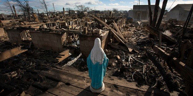 FILE PHOTO: 'BEST PHOTOS OF 2012' (***BESTOF2012***): A statue of the Virgin Mary stands over houses destroyed by fire in the Breezy Point neighborhood of the Queens borough of New York, U.S., on Wednesday, Oct. 31, 2012. Atlantic superstorm Sandy may cut U.S. economic growth as it keeps millions of employees away from work and shuts businesses from restaurants to refineries in one of the nationÃs most populated and productive regions. Photographer: Scott Eells/Bloomberg via Getty Images