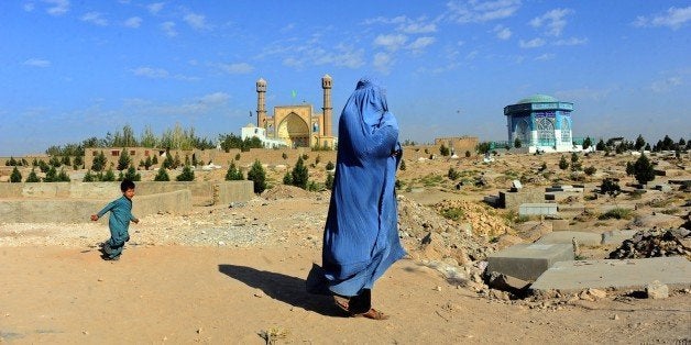 A burqa clad-Afghan woman walks near a cemetery in Herat province on October 12, 2014. Afghanistan's economy has improved significantly since the fall of the Taliban regime in 2001 largely because of the infusion of international assistance. Despite significant improvement in the last decade the country is still extremely poor and remains highly dependent on foreign aid. AFP PHOTO/AREF KARIMI (Photo credit should read Aref Karimi/AFP/Getty Images)