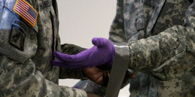 Army Stf. Sgt. Samuel Hines, left, helps Cpl. Zachary Wicker tape gloves to his uniform in Fort Bliss, Texas, Tuesday, Oct. 14, 2014. About 500 Fort Bliss soldiers are preparing for deployment to West Africa where they will provide support in a military effort to contain the Ebola outbreak. (AP Photo/Juan Carlos Llorca)