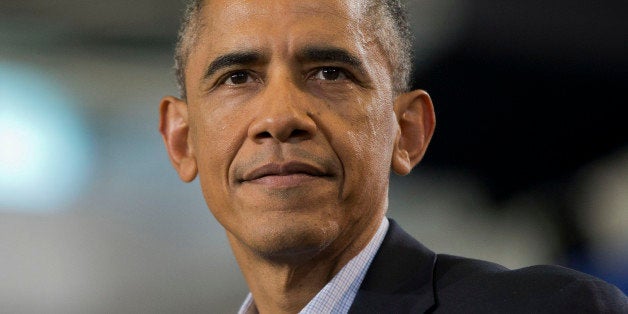 President Barack Obama pauses as hecklers in the audience interrupt his speech during a campaign event for gubernatorial candidate Dan Malloy at Central High School in Bridgeport, Conn., Sunday, Nov. 2, 2014. (AP Photo/Pablo Martinez Monsivais)