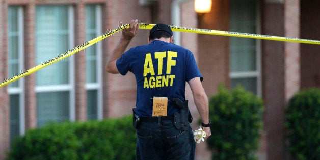 An ATF agent lifts crime scene tape outside the scene of two murders Thursday morning, Aug. 8, 2013, in DeSoto, Texas. Four p