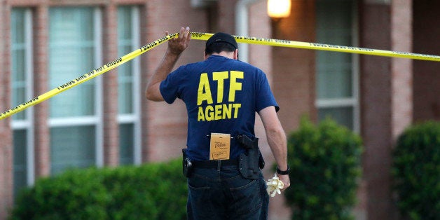 An ATF agent lifts crime scene tape outside the scene of two murders Thursday morning, Aug. 8, 2013, in DeSoto, Texas. Four people were killed at two different locations in South Dallas County and the suspected shooter is in police custody. (AP Photo/LM Otero)