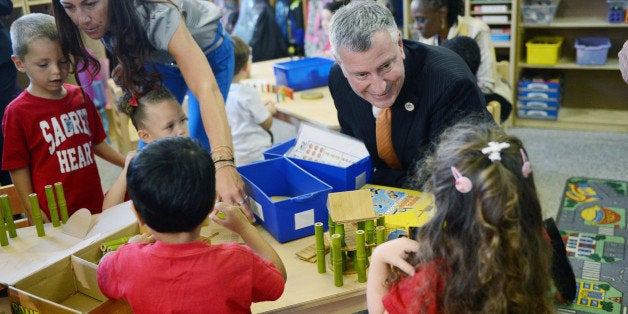 Mayor Bill de Blasio visits a prekindergarten class on Thursday, Sept. 4, 2014 at the Sacred Heart School in the Staten Island borough of New York on the first day for the city's public schools and the first day of his expansion of early childhood education. At left is teacher Corie Caccese. (AP Photo/Pool, New York Daily News, Susan Watts)