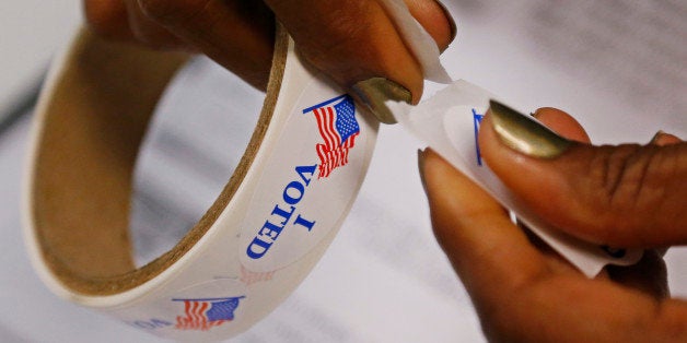 A poll worker rips "I Voted" stickers from a roll at a polling place in Oklahoma City, Tuesday, June 24, 2014. With both of Oklahoma's U.S. Senate seats on the ballot for the first time in recent history, incumbent Jim Inhofe is seeking to fend off challengers in the Republican primary for one of the seats while two of the party's ascending stars battle for the other. (AP Photo/Sue Ogrocki)