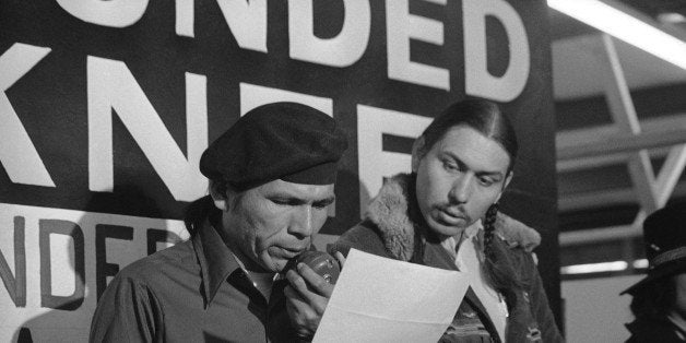 File - In this March 18, 1973 file photo taken in Wounded Knee, S.D., American Indian Movement leader Dennis Banks, left, reads an offer by U.S. government seeking to effect an end to the Native American takeover of Wounded Knee. Looking on is AIM leader Carter Camp. Camp, a longtime activist with the American Indian Movement who was a leader in the Wounded Knee occupation in South Dakota, died Dec. 27, 2013, in White Eagle, Okla. He was 72. (AP Photo/Jim Mone, File)