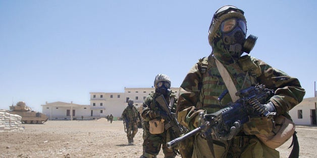 US Army soldiers from 2-8 Infantry, 2nd Brigade, 4th Infantry Division wearing their full chemical protection suits walk inside the courtyard of an industrial complex they secured which they thought was a possible site for weapons of mass destruction in the central Iraqi town of Baquba 01 May 2003. The building was secured without any incidents and no WMD were found. The building was used as a bread factory. AFP PHOTO/