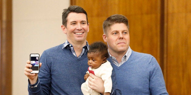 Jim, left, and Jason Shaffer, hold their daughter Norah, 3 mo., while being married in a group by the Oakland County Clerk in
