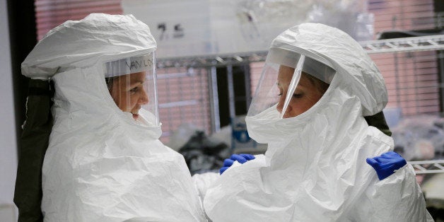 FILE- In this Oct. 24, 2014, file photo, members of the Department of Defense's Ebola Military Medical Support Team assist each other with their protective gear during training at San Antonio Military Medical Center in San Antonio. Even small clusters of Ebola cases could overwhelm parts of US medical care system, according to an Associated Press review of readiness at hospitals and other components of the emergency medical network. (AP Photo/Eric Gay, File)