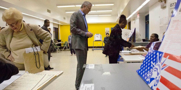 New York Mayor Bill de Blasio, center, waits behind first lady Chirlane McCray as they prepare to vote on Election Day, Tuesday Nov. 4, 2014, in New York. (AP Photo/Bebeto Matthews)