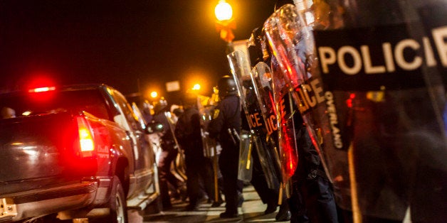 FERGUSON, MO - NOVEMBER 19: Police surge into the street through cars in order to clear of protestors in front of the the Ferguson Police Department during continued demonstrations in regards to the shooting death of Michael Brown by police officer Darren Wilson in Ferguson, Missouri, USA, on November 19, 2014. People are waiting for the grand jury decision in the case of 18 year-old black teenager shot and killed by a police officer, in Ferguson, Missouri. (Photo by Samuel Corum/Anadolu Agency/Getty Images)