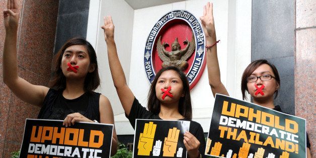 MANILA, PHILIPPINES - 2014/06/05: Members of Akbayan-Youth protest in front of the Royal Thai Embassy in Makati City (Southeast of Manila) to express their solidarity to the Thai people who are under military rule, following a military coup last May 22, 2014. The group also flash a three-finger salute borrowed from the 'The Hunger Games', a popular book trilogy and movie series and the group also taped their mouths as a sign of their silent protest. The group conducted a public reading of books in solidarity with the youth people in Thailand who have taken such non-violent means to show defiance against the junta-led Thailand. (Photo by Gregorio B. Dantes Jr/Pacific Press/LightRocket via Getty Images)