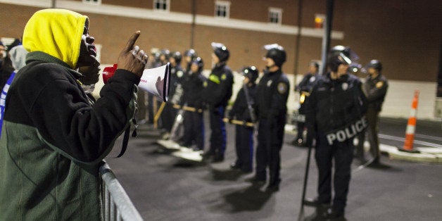 FERGUSON, UNITED STATES - NOVEMBER 20: Protestors yell at a line of Police Officers at the Ferguson Police Department during ongoing protests after the shooting death of Michael Brown by Officer Daren Wilson in Ferguson, Mo, on November 20, 2014. (Photo by Samuel Corum/Anadolu Agency/Getty Images)