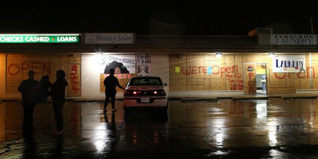 FERGUSON, MO - NOVEMBER 22: People stand in the parking lot of boarded up businesses on November 22, 2014 in Ferguson, Missouri. Tensions in Ferguson remain high as a grand jury is expected to decide soon if Ferguson police officer Darren Wilson should be charged in the shooting death of Michael Brown. (Photo by Justin Sullivan/Getty Images)