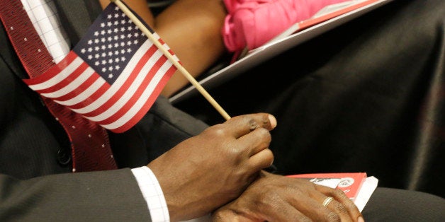 A new United States citizens holds an American flag during a naturalization ceremony, Wednesday, July 9, 2014 in New York. Deputy Secretary of Homeland Security Alejandro Mayorkas administered the Oath of Allegiance to 75 citizenship candidates at the 85th Annual League of United Latin American Citizens (LULAC) Convention. (AP Photo/Mark Lennihan)