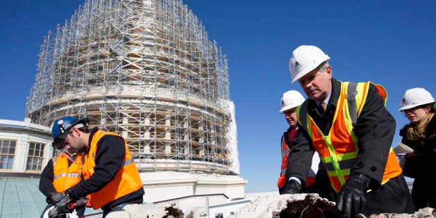 Sen. John Hoeven, R-N.D., second from right, reaches for a cast iron detail in need of repair during a news conference on the roof of the Capitol Building in Washington, Tuesday, Nov. 18, 2014, to announce the completion of the scaffolding and the start of the repairs for the Capitol Dome Restoration Project. (AP Photo/Carolyn Kaster)