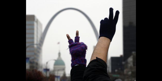 Protesters hold up peace signs as they block an intersection in downtown St. Louis, Wednesday, Nov. 26, 2014. Since a grand jury's decision was announced Monday night, Nov. 24, not to indict a white Ferguson, Mo., police officer who killed Michael Brown, an unarmed black teen, protesters in cities throughout the country have rallied behind the refrain "hands up, don't shoot," and drawn attention to other police killings. (AP Photo/Charlie Riedel)