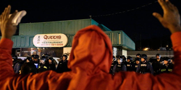 FERGUSON MO - NOVEMBER 29 : A demonstrator protesting the shooting death of Michael Brown confronts police officers with his hands up November 29, 2014 in Ferguson, Missouri. Brown, a 18-year-old black male teenager was fatally wounded by Darren Wilson, a white Ferguson, Missouri Police officer on August 9, 2014. A St. Louis County 12-member grand jury who reviewed evidence related to the shooting decided not to indict Wilson with charges sparking riots through out Ferguson. (Photo by Joshua Lott/Getty Images)