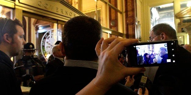 In this photo taken Feb 2, 2012, cell phones are used to record Henry Bayer, executive director of AFSCME Council 31, right, while protesting and being confronted by the Illinois Secretary of State Police, as other members of the American Federation of State, County and Municipal Employees union also protest in front of the governor's office, demanding that Illinois Gov. Pat Quinn pay them raises he has withheld, at the Illinois State Capitol in Springfield, Ill. In the era of smart phones and YouTube, many people have grown used to recording their lives, from fun moments with friends to tense encounters with police. Some have discovered the hard way that this can result in felony charges, for recording their arrest for peddling without a license, for instance, or taping police in a dispute about old cars on a lawn. Many more people could be introduced to the Illinois law in May when thousands of protesters and journalists head to Chicago for the NATO and G8 summits. (AP Photo/Seth Perlman)