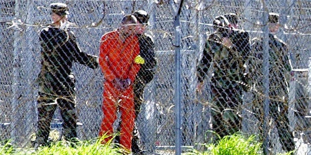 Guantanamo Bay, CUBA: FOR USE WITH AFP STORIES: US-attacks-UN-Guantanamo (FILES) This 17 January, 2002, file photo shows a detainee (2nd L) wearing an orange jump suit surrounded by heavy security at the US Guantanamo Naval Base in Cuba. UN experts said on 16 February, 2006, the US must shut down the detention center without delay and release or try its inmates. The demand came in a report by five independent experts who act as monitors for the UN Human Rights Commission. The document charged that US treatment of the more than 500 'war on terror' detainees held in legal limbo at the naval base in Cuba violated their rights to physical and mental health and in some cases amounted to torture. The White House blasted the UN report, alleging abuse of inmates and calling for closing the facility, as 'a discredit to the UN.' AFP PHOTO/ROBERTO SCHMIDT/FILES (Photo credit should read ROBERTO SCHMIDT/AFP/Getty Images)